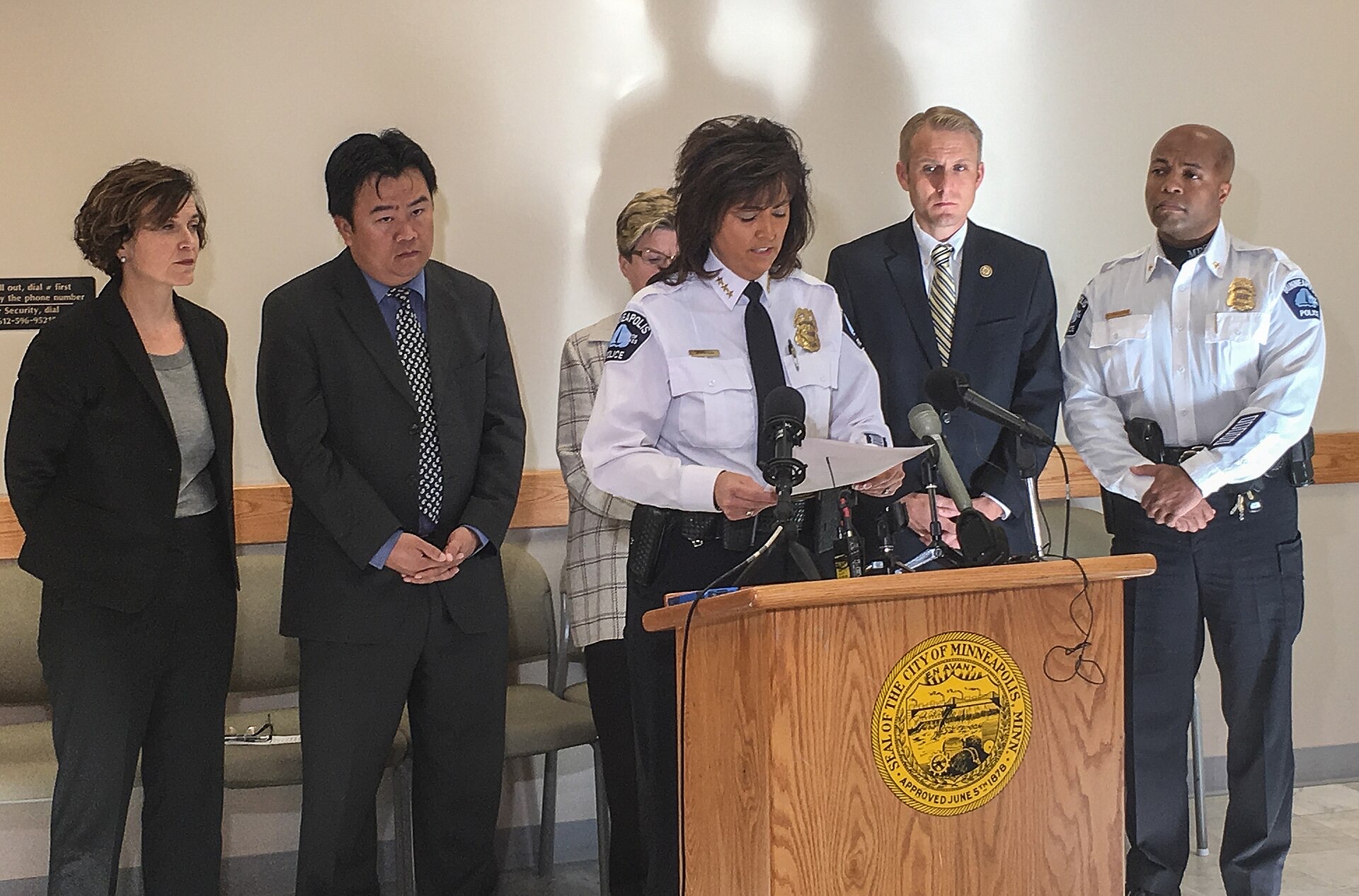A uniformed police chief reading a prepared statement at a podium of news microphones during a press conference